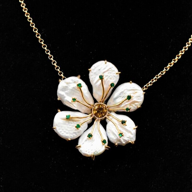 a necklace with white flowers on a gold chain